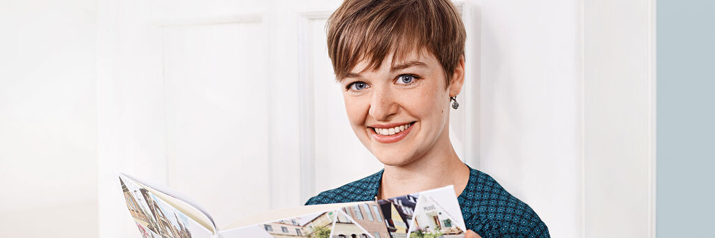 Person holds a CEWE photo book and looks at it with joy
