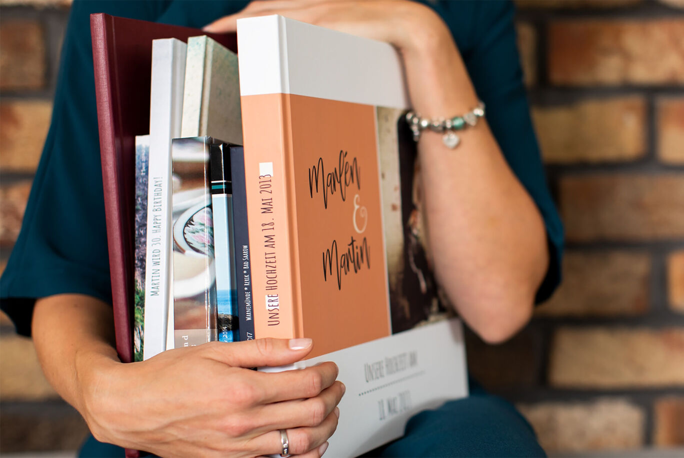 A woman holding a CEWE photo book titled 'Moments & Features' and smiling.