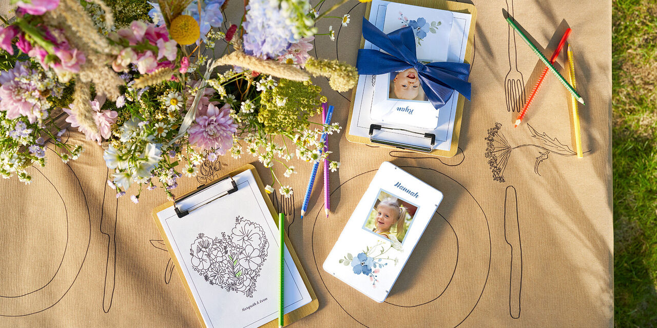 Sur une table, des crayons de couleur dans une boîte métallique au design floral avec une photo d’enfant et une image à colorier.